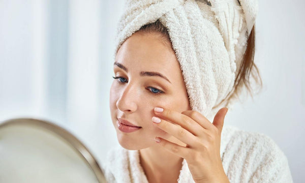 Woman looking at skin in mirror