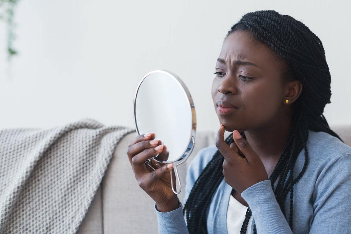 Woman looking at her skin in the mirror